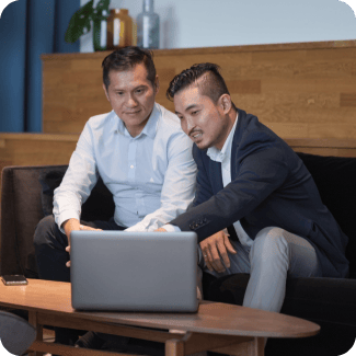 Two men sitting on a couch looking at a laptop.