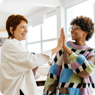 Two women high fiving each other.