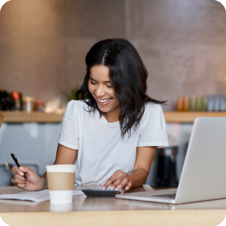 Young woman sitting at a desk smiling while look at her work.