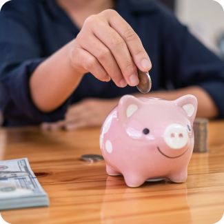 Woman adding coins to her pink piggy bank.