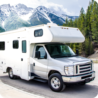 Large white RV driving through a mountain range in the spring.