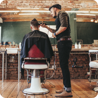 Hipster man cutting his clients hair in a barber shop.