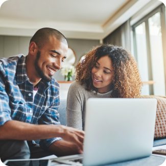 Young couple sitting together looking at laptop screen.