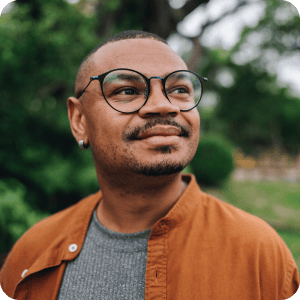 Black man with glasses smiling.