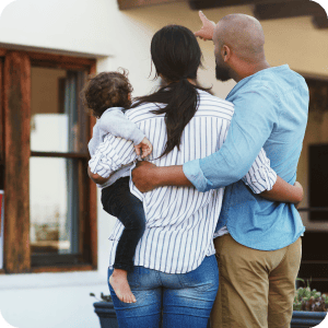 Couple holding baby looking at their new home.