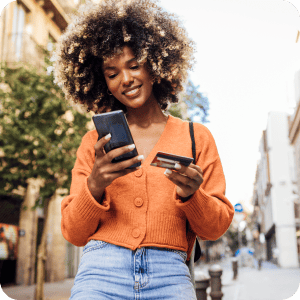 Woman with afro walking while looking at her phone.