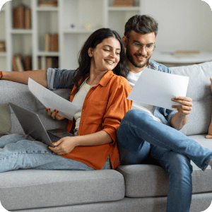 Couple sitting on a couch looking at documents.