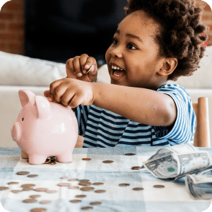 Young kid holding coin above a piggy bank.