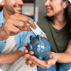 Man putting cash in a piggy bank.