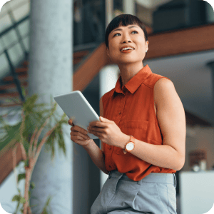 Woman holding a tablet looking to the side.