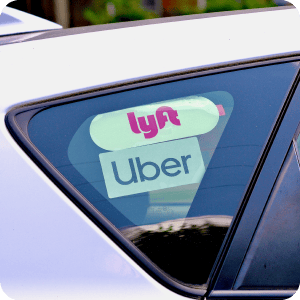 Car window with a Lyft and Uber sticker.