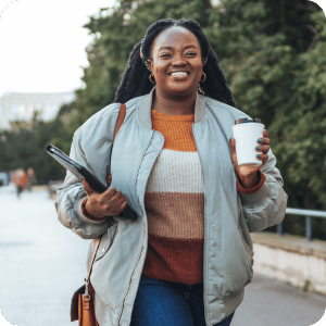 Happy woman walking with a coffee in her hand.