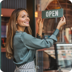 Female small business owner turning the sign on her front door to open.