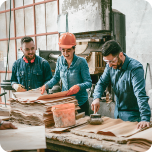 Factory workers smiling at each other while working.