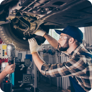 Male mechanic working under a vehicle to adjust the tire alignment.