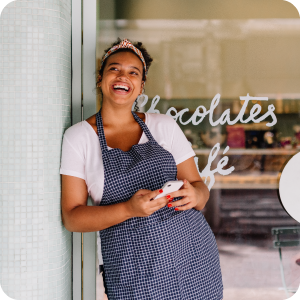 Female small business owner standing outside her shop smiling.