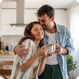 Happy couple holding each other and drinking coffee.