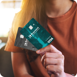 Close up of a woman holding the Rivermark Platinum and Cash Back credit cards.