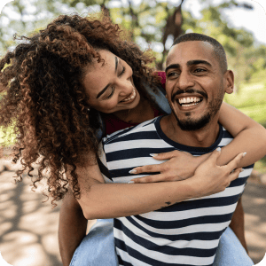 Guy giving his girl friend a piggy back ride while she stares at him lovingly.