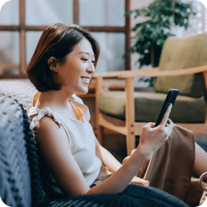 Happy woman sitting on the floor looking at her cell phone.