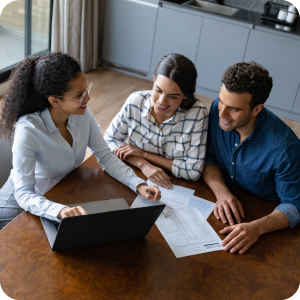 Married couple sitting at a desk with a financial advisor looking at a computer screen.