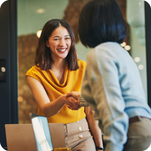 Two women smiling and shaking hands.