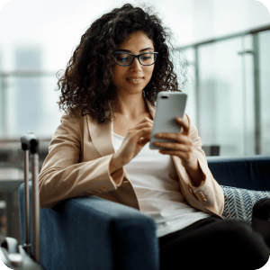 Woman with curly hair looking at her phone while sitting.