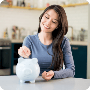 Happy woman putting coins in a blue piggy bank.