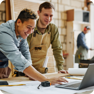 Small business owners looking at a laptop together while smiling.