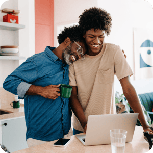 Father and son embracing while looking at a computer.