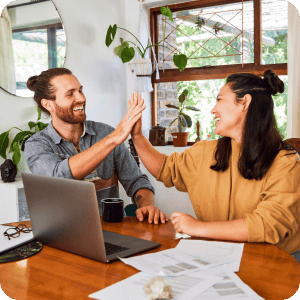 Happy couple high fiving while looking at a computer.