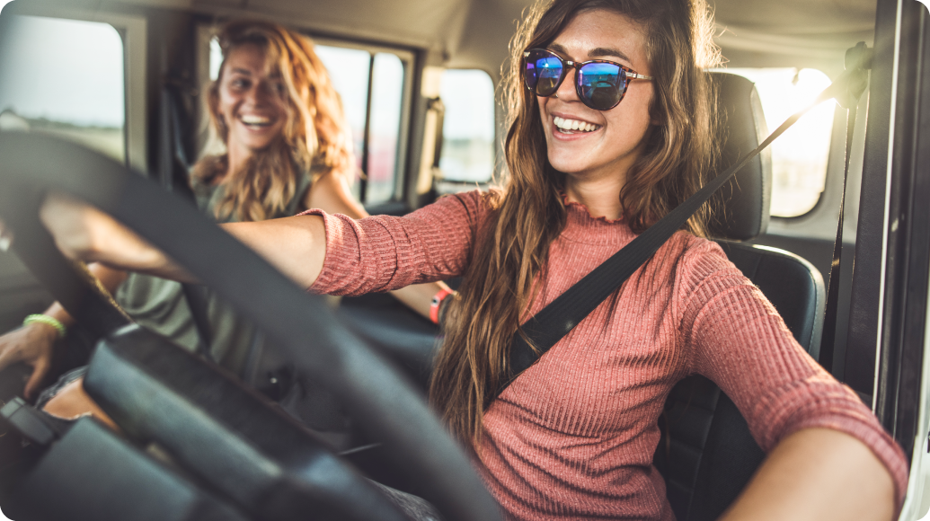 Woman driving a car with her friend in the passenger seat.