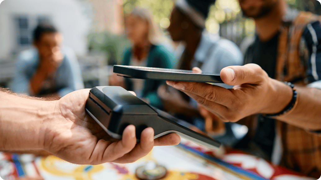 Hand holding a cell phone and using it to pay for their meal with mobile wallet.